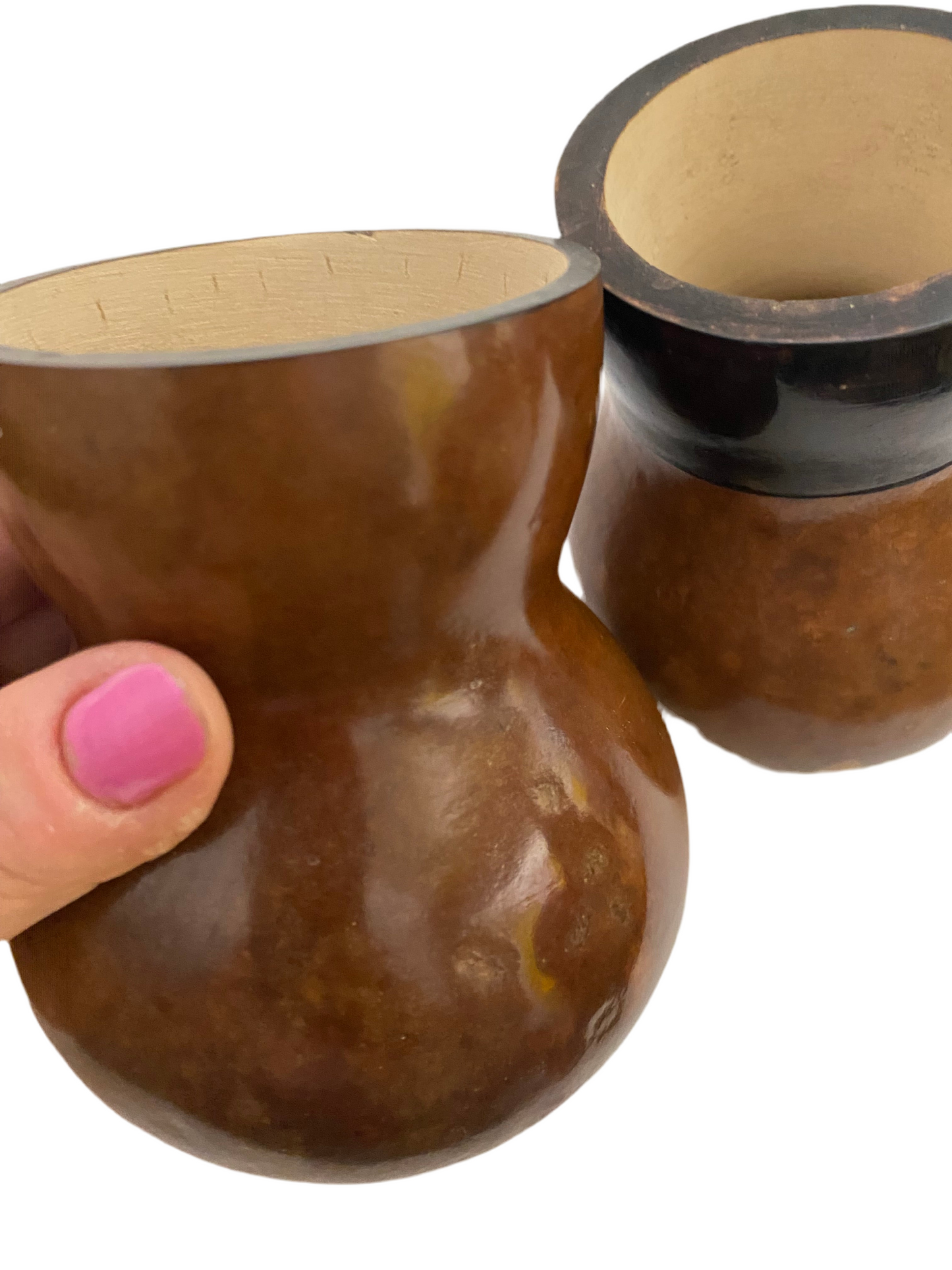 Getúlinho gourd being held up with a hand and another one in the background against a white background.