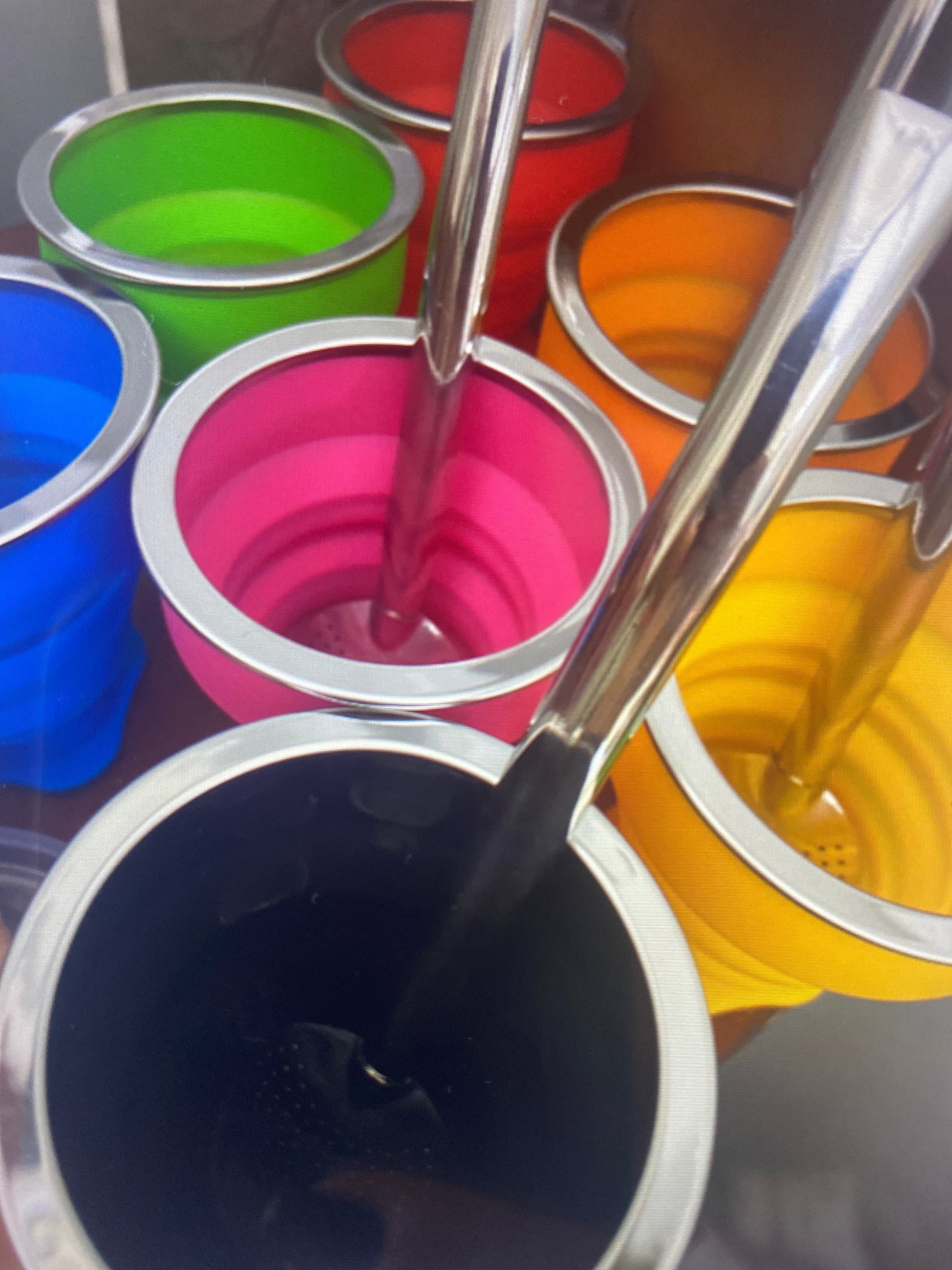 An assortment of colorful silicone cups in various colors including green, pink, yellow, and black, with metal straws inserted into them.