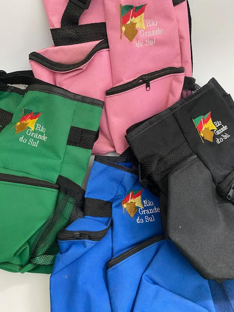 A collection of four carrying cases for mate, displayed in pink, green, blue, and black colors, with a logo and the text 'Rio Grande do Sul' on them.