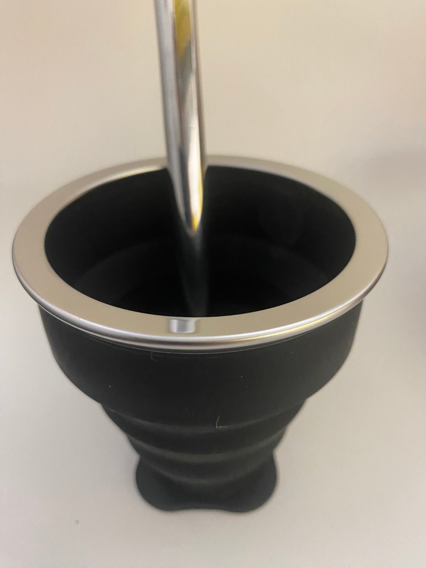A blackj silicone collapsible cup with a metallic top, likely used for serving or drinking Mate.