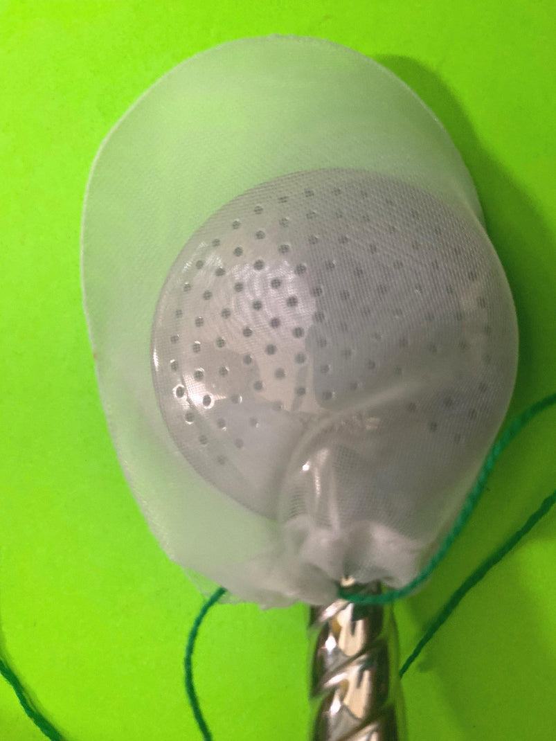 A yerba mate bombilla filter covering a bombilla over a green background. 