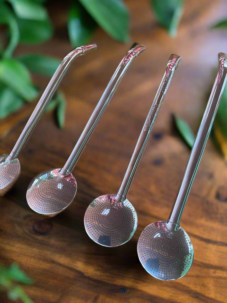 4 bombillas on a wooden table with leaves in a the blurred background