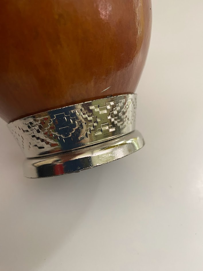 Close up of a yerba mate gourd and i'ts metal engraved base.
