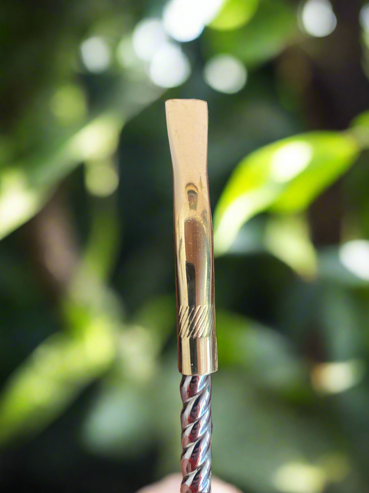 Gold-colored bombilla with a twisted design against a blurred green background