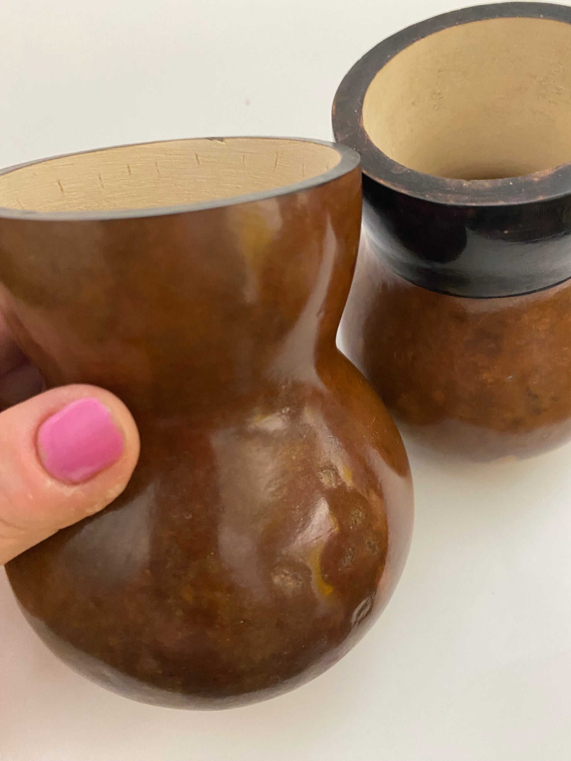 Getúlinho gourd being held  up with a hand and another one in the background. 