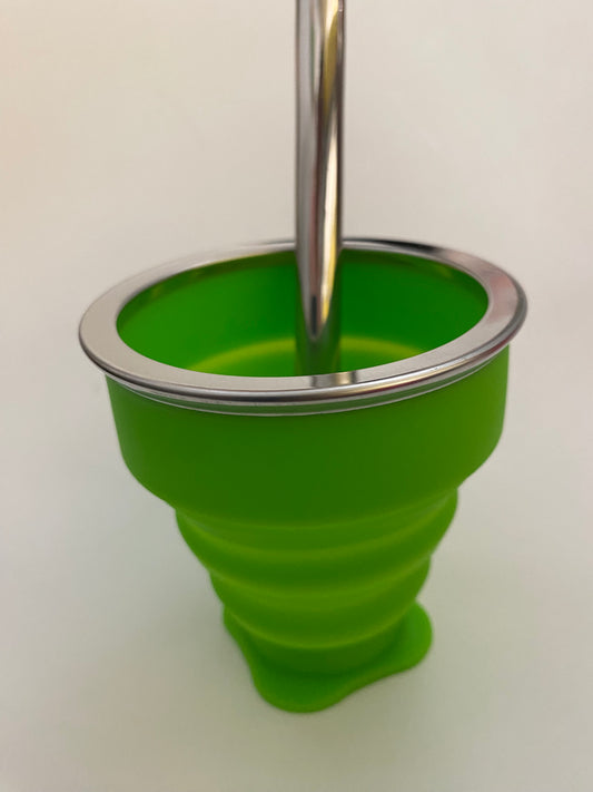A green silicone collapsible cup with a metallic top, likely used for serving or drinking Mate.