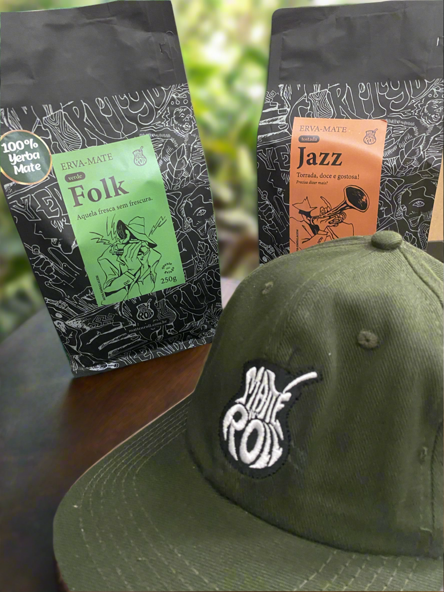 A forest green hat in the foreground wiht two bags of yerba mate, one with a green label reading FOLK, another with an orange label reading Jazz.