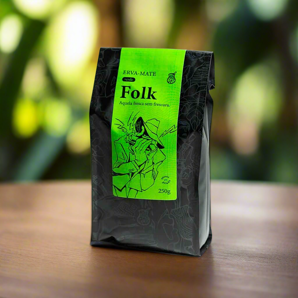 A package of Matte N Roll Folk yerba mate with a green label, displaying the brand and product name, placed on a wooden surface with a green, leafy background.