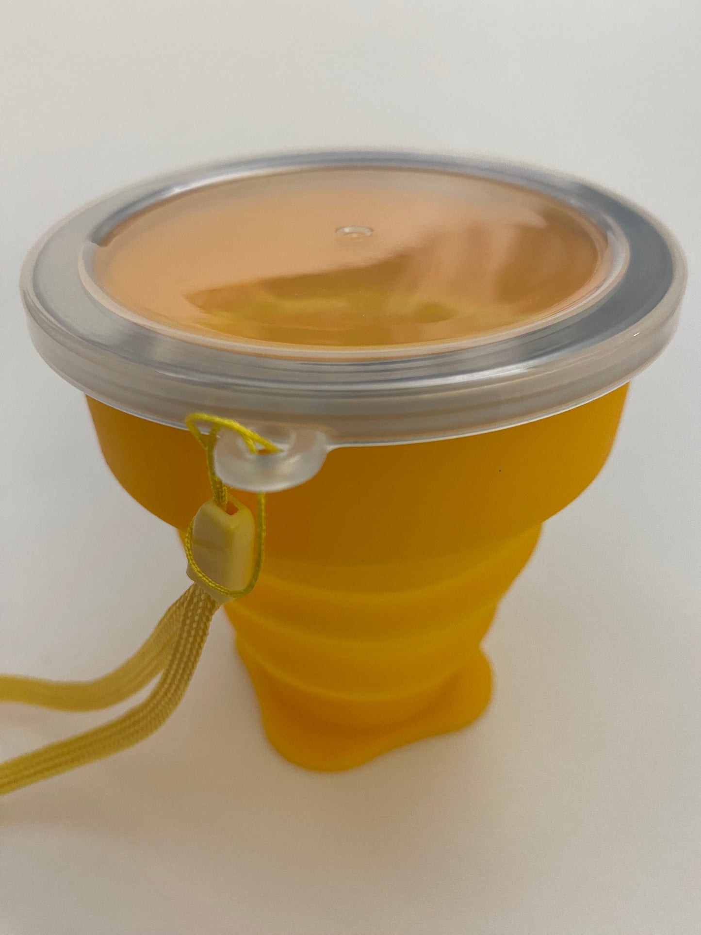 A yellow silicone collapsible cup with a metallic top, likely used for serving or drinking Mate.