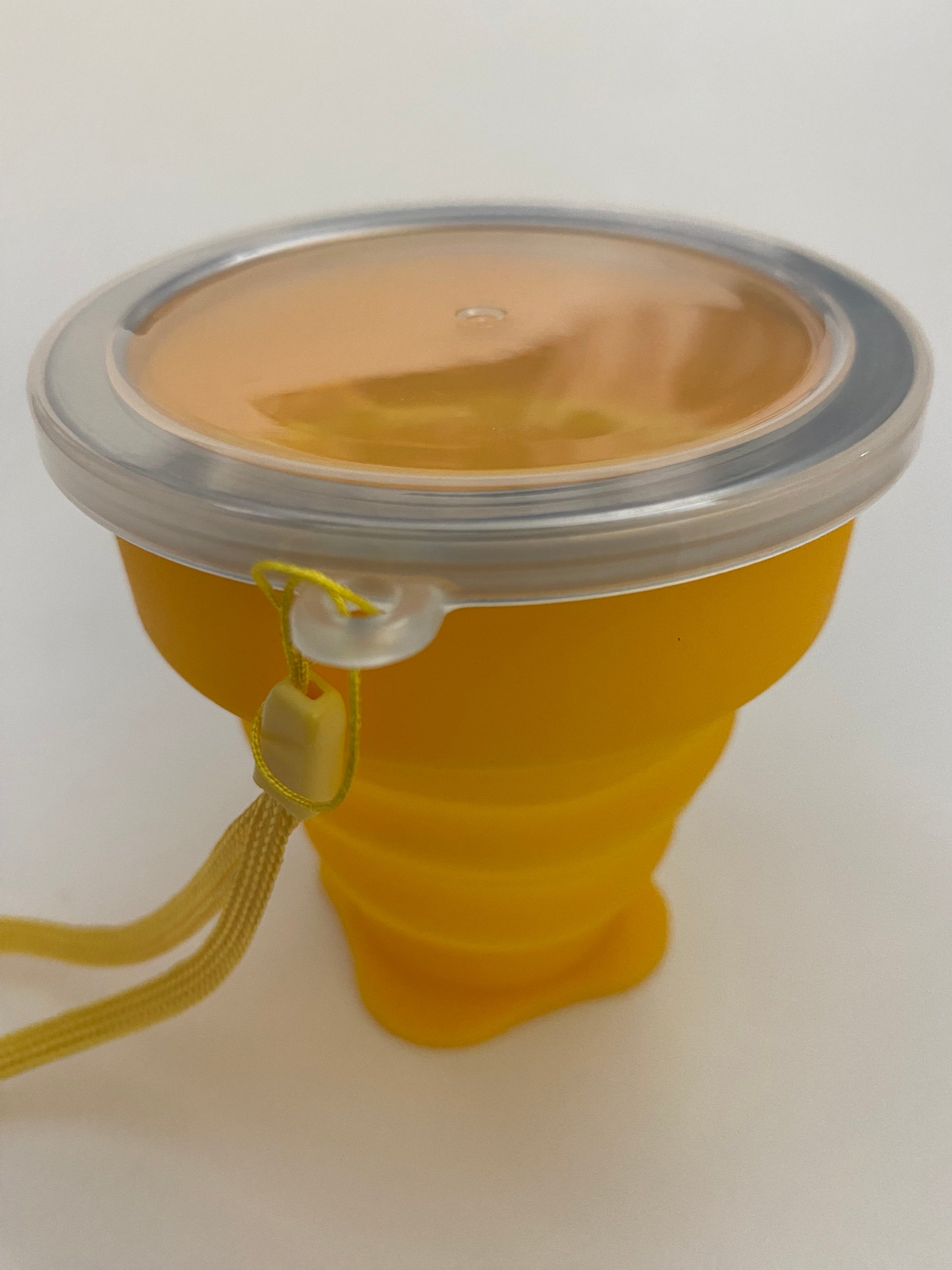 A yellow silicone collapsible cup with a metallic top, likely used for serving or drinking Mate.