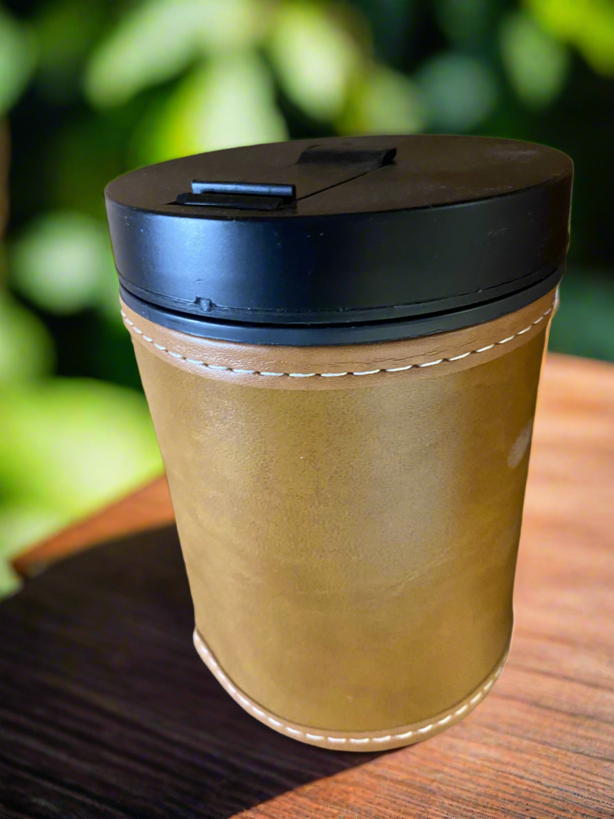 Yerbera with black lid on a wooden surface with a blurred green background

